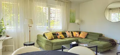 a living room with a green couch and some windows at Spacious 3 room close to tram and amenities in Nice