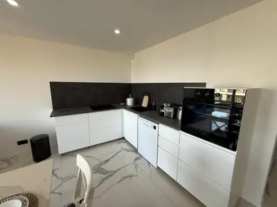 a kitchen with white cabinets and a black appliance at Sea View, Modern Apartment and Terrace in Nice