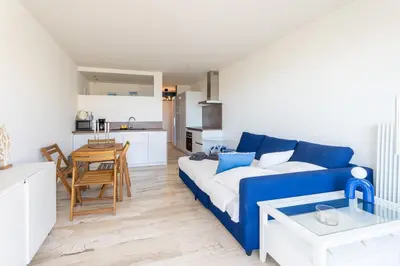 a living room with a blue couch and a kitchen at Azzuro - Mare e Terrazza in Nice
