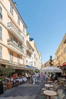 a group of people walking down a street with tables and chairs at Nice Renting - 6C FRANCE - Chic Stay Pedestrian Zone Sea Massena in Nice