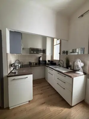 a kitchen with white cabinets and a wooden floor at Studio proche gare in Nice