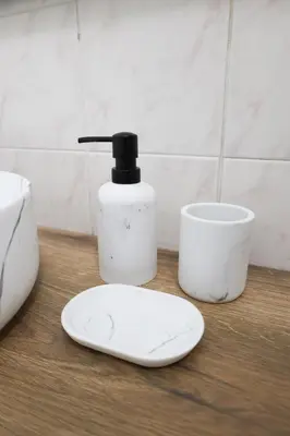 a white plate next to a bottle of soap and a cup at Carre d'OR Massena luxury apartment in Nice