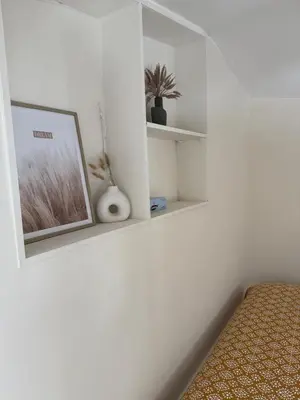 a bedroom with white walls and a picture on a shelf at Charmant appartement, piscine 15 min de Nice in Carros