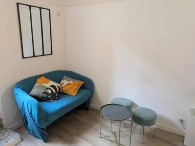 a living room with a blue couch and two stools at Studio 4 couchages in Nice