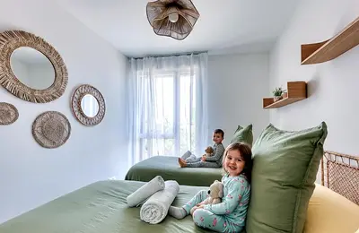two children sitting on a bed in a bedroom at Les Vagues du 5e 4 personnes , 2 chambres , clim , wifi , Cap3000 à pied , parking in Saint-Laurent-du-Var