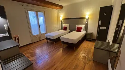 a hotel room with two beds and wooden floors at T2 Pasteur in Nice
