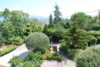 a large swimming pool with a red umbrella and chairs at Villa Nice Côte d'Azur piscine privée rez de chaussée in La Gaude