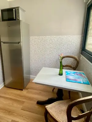 a table with a vase of flowers and a refrigerator at Villa Nice Côte d'Azur piscine privée rez de chaussée in La Gaude