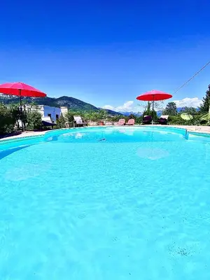 a large swimming pool with two red umbrellas at Villa Nice Côte d'Azur piscine privée rez de chaussée in La Gaude