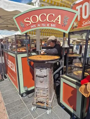a person sitting at a food stand with a pizza at Central & Beach in Nice
