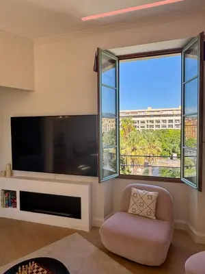 a living room with a large television and two windows at Central & Beach in Nice