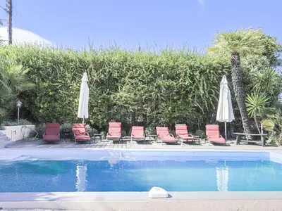 a group of chairs and umbrellas next to a pool at Holiday Home Les Genêts by Interhome in Nice