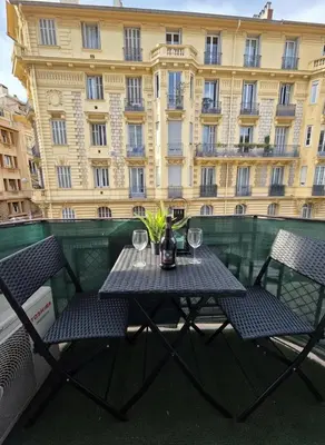 a table with glasses and a bottle of wine on a balcony at Cozy studio, balcony & AC, Heart of Nice in Nice