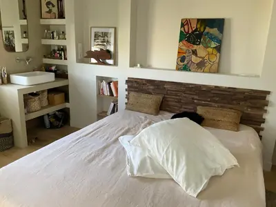a bedroom with a white bed with a brick wall at Maison avec vue mer et jacuzzi à 15 mn du centre in Nice