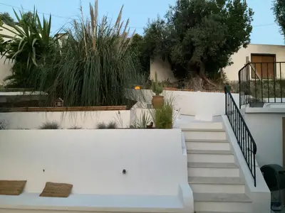 a white bench in front of a building with stairs at Maison avec vue mer et jacuzzi à 15 mn du centre in Nice