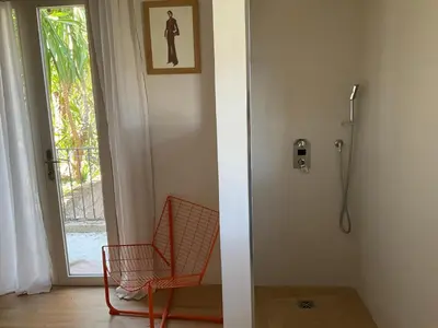 a bathroom with a shower and a chair next to a door at Maison avec vue mer et jacuzzi à 15 mn du centre in Nice