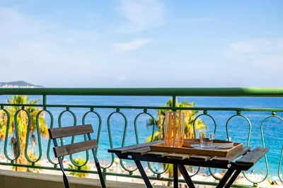 a table on a balcony with a view of the ocean at Appartement Prestige sur la Promenade des Anglais in Nice
