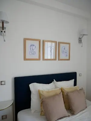 a bed with four pictures on the wall above it at Appartement Prestige sur la Promenade des Anglais in Nice