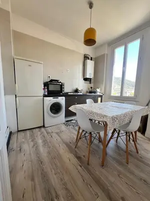 a kitchen with a table and a white refrigerator at Charmant et cosy 3pcs in Nice