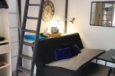 a living room with a black couch and a clock at Cozy apartment in Nice Est in Nice