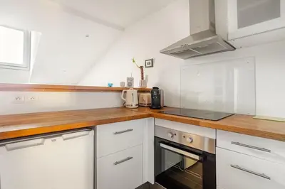 a kitchen with white cabinets and a wooden counter top at Cosy 2 pieces au Coeur du Centre Ville in Nice