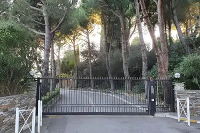 a black iron gate with trees in the background at CASA-Martine vue sur mer et parking privé in Nice