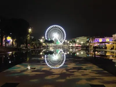 a ferris wheel in a city at night at Appartements Massena in Nice
