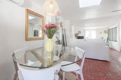 a glass table with white chairs and a vase with flowers at Le Collet - appt climatisé proche plage in Nice