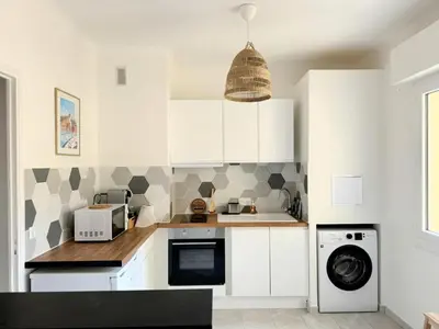 a kitchen with white cabinets and a washer and dryer at Charmant studio près de la plage et la Promenade des Anglais in Nice
