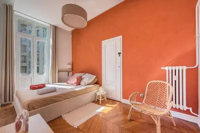 a bedroom with a bed with an orange wall at Soleil Niçois Terracotta in Nice