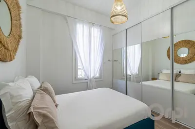 a white bedroom with two beds and a mirror at New Cosy Apartment Libération in Nice