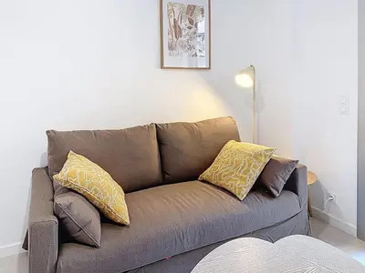 a brown couch with yellow pillows in a living room at Charmant 2P neuf avec terrasse, proche mer in Nice