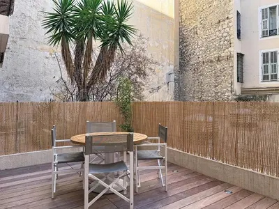 a table and chairs on a patio with a palm tree at Charmant 2P neuf avec terrasse, proche mer in Nice