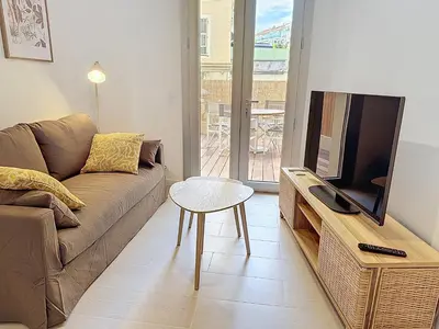a living room with a couch and a tv and a table at Charmant 2P neuf avec terrasse, proche mer in Nice