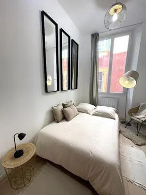 a bedroom with a large white bed and a table at Studio Vieux-Nice proche de la mer et Cours Saleya in Nice
