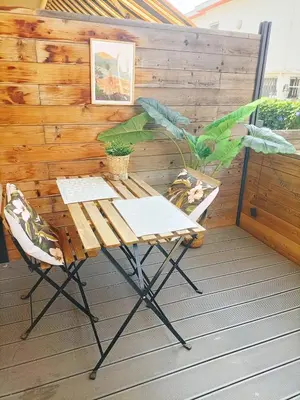 a table and chairs on a deck with a wooden wall at Apartsuite jardin Nice cap 3000 bord de mer in Saint-Laurent-du-Var
