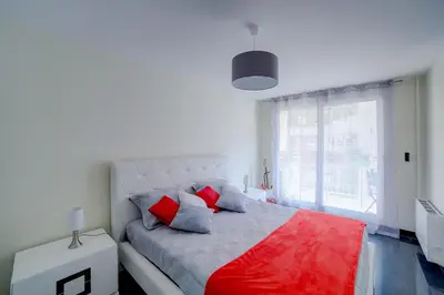 a bedroom with a bed with red pillows and a window at Appartement luxueux entier 3 chambres in Nice