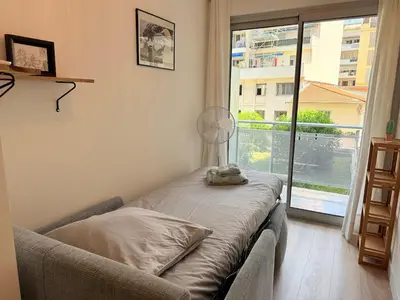 a room with a couch and a window with a fan at Spacieux 3 pièces Gambetta, proche Tramway in Nice
