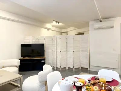a room with a table and white chairs and a television at Appartement à 100 m de la mer avec stationnement gratuit in Nice