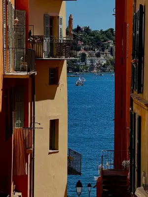 a view of the water from between two buildings at Duplex design - Old Town 50 m from the sea in Villefranche-sur-Mer