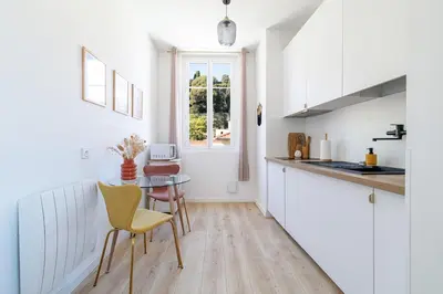a kitchen with white cabinets and a table and chairs at Cozy and bright appartement - Port of Nice in Nice
