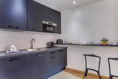 a kitchen with black cabinets and a sink and two chairs at ESCAPADE AP4463 By Riviera Holiday Homes in Villefranche-sur-Mer