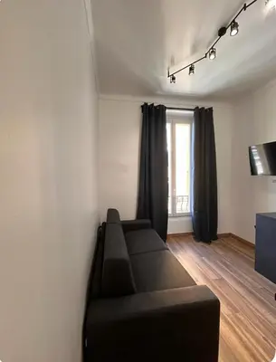 a living room with a black couch and a window at Jolie studio in Nice