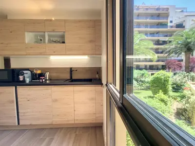 a kitchen with wooden cabinets and a large window at Nestor&Jeeves - PALM RIVIERA - Central - Close Old Town in Nice