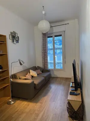 a living room with a couch and a television at Deux pièces Libération - Balcon in Nice