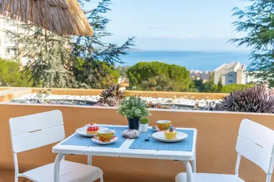 a blue table with plates of food on a balcony at Pleine vue mer au calme - Parking, Piscine, Tennis in Nice