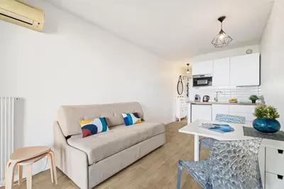 a living room with a couch and a kitchen at Pleine vue mer au calme - Parking, Piscine, Tennis in Nice