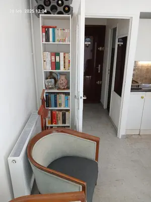 a room with a chair and a book shelf with books at Studio Proche mer Nice in Nice