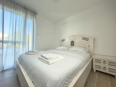 a white bedroom with a bed with towels on it at L'Elydris - Piscine Wifi Rooftop in Saint-Laurent-du-Var