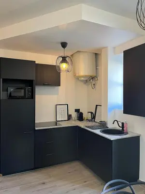 a kitchen with black cabinets and a sink at Charmant 2 pièces - Hyper Centre de Nice in Nice